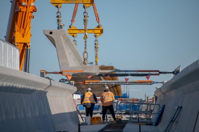 Bridge beam being lifted into place on a rail project